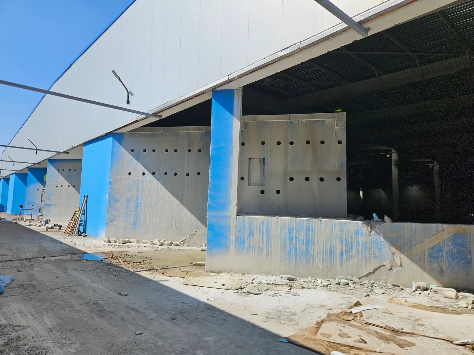 Rows of clustered core-drilled holes through industrial concrete walls on a commercial project