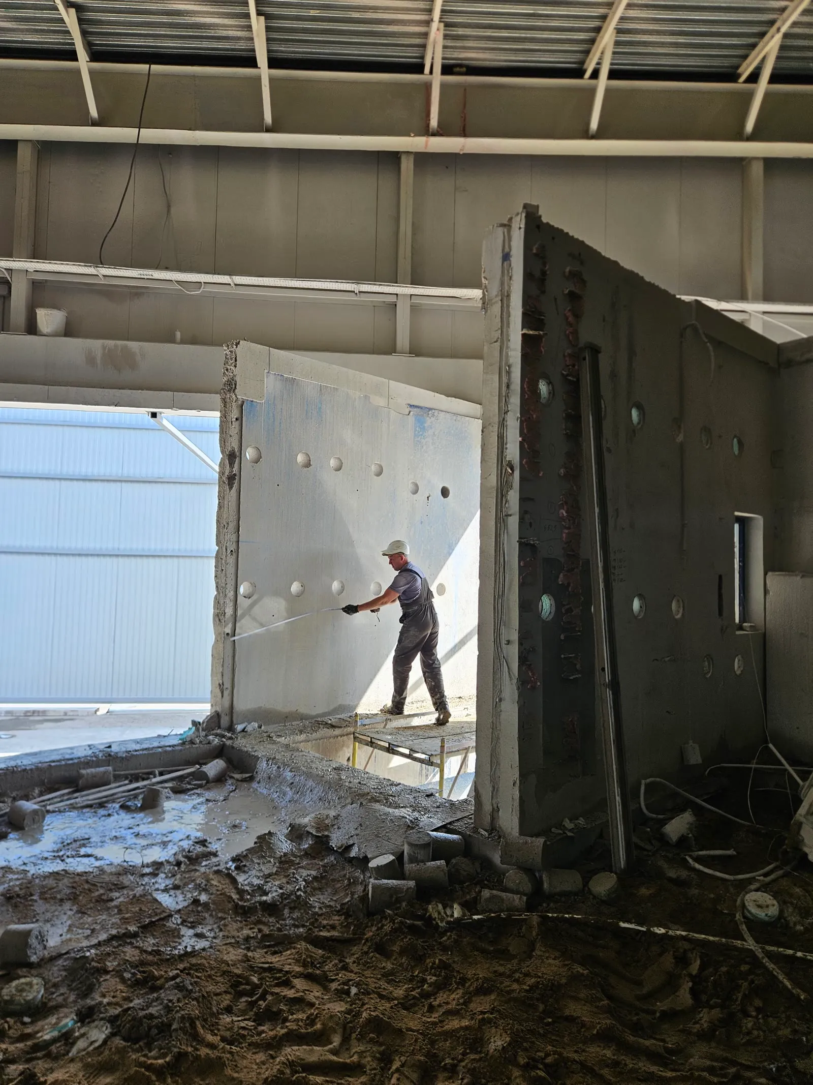 Two operators core drilling a blue industrial wall from a scaffold