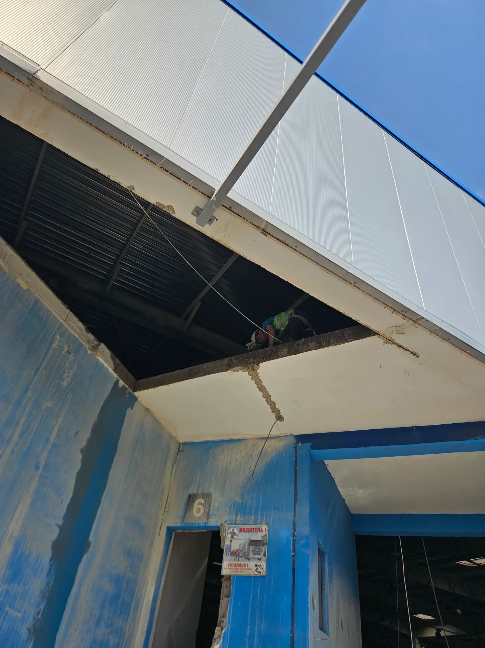 Operator cutting the top of a concrete wall with sparks, round core holes below