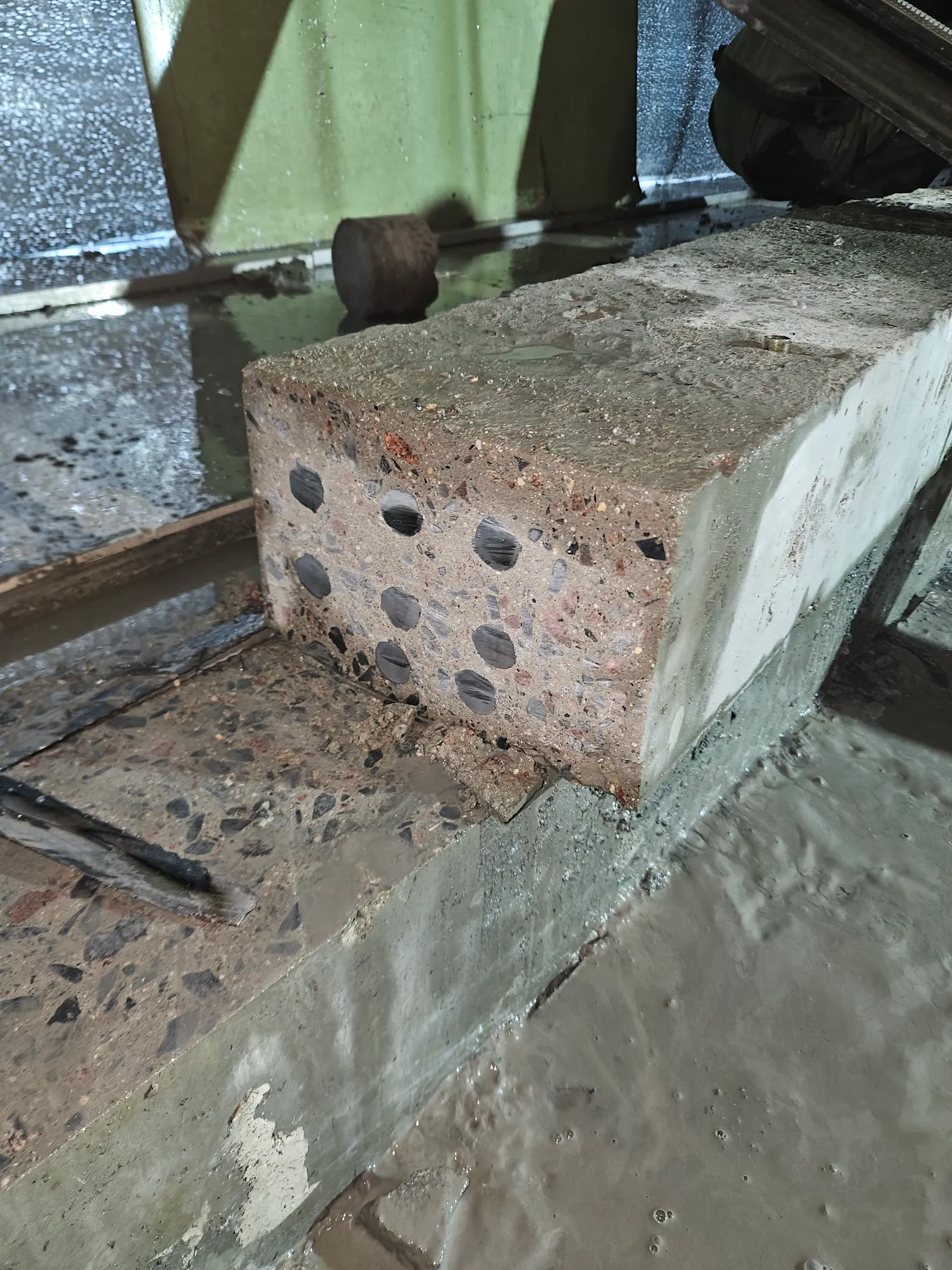 Slab saw cutting a concrete beam with a fountain of sparks in a dark industrial hall