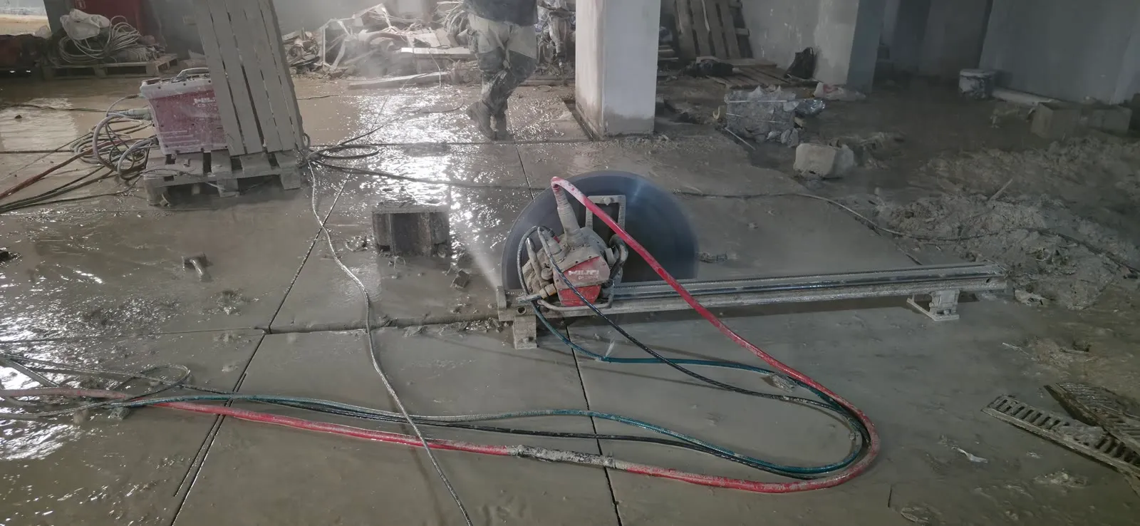 Track saw cutting a concrete floor slab into removal sections with wet cutting